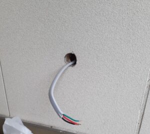壁の丸い穴から電線が出ている